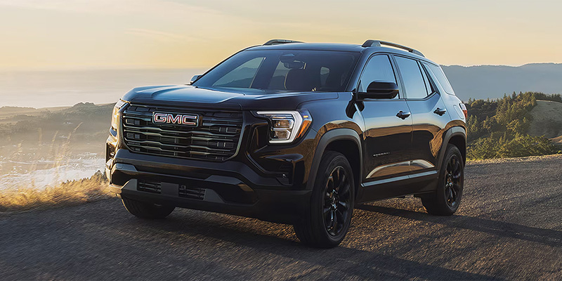 2026 GMC Terrain silver-gray SUV cruising on a road, highlighting its refined styling, smooth performance, and everyday versatility.
